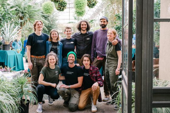 a group of people smiling at the camera inside a conservatory